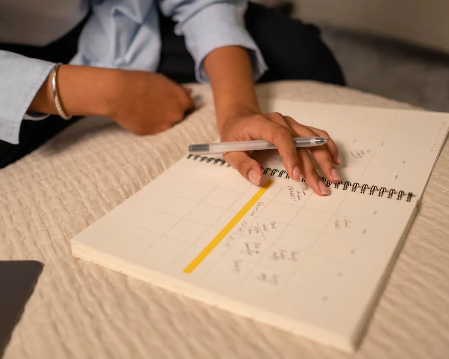 A hand writing in a spiral planner